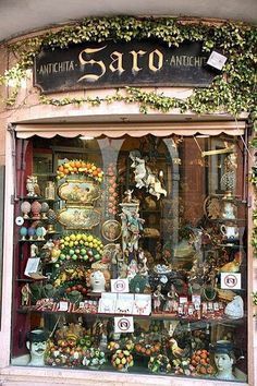 a store front with many different items on display in it's glass window displays an assortment of vases and flowers