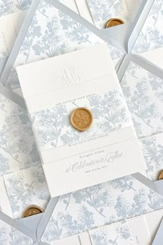 the wedding stationery is laid out on top of white envelopes with gold buttons