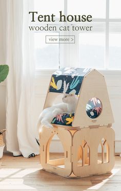 a cat sitting on top of a wooden house in the middle of a living room