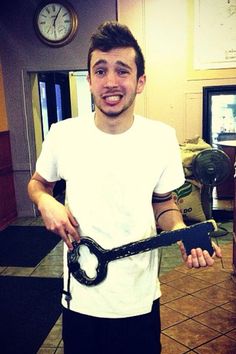 a man holding a clock in his hands and smiling at the camera while standing in a kitchen