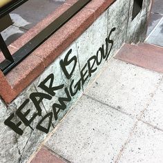 graffiti writing on the side of a building next to a metal bench with a yellow fire hydrant