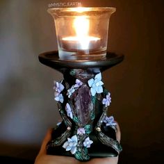 a hand holding a candle holder with flowers on it