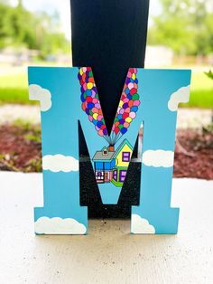 the letter m is decorated with balloons and houses