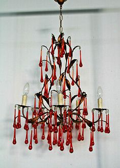 a chandelier hanging from the ceiling with red glass drops and candles on it