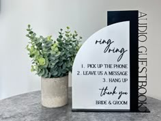 a white and black sign sitting next to a potted plant