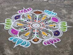 an intricately painted design on the ground in front of a stone wall with leaves and flowers