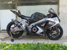 a silver and black motorcycle parked in front of a building with green plants around it