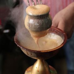 a person is pouring something into a bowl with steam coming out of it and on top of the stand