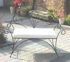 a bench sitting on top of a brick patio next to flowers and potted plants