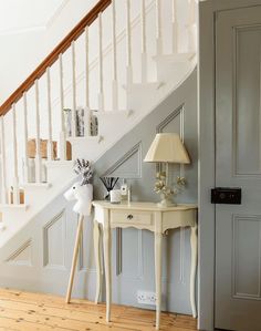 a white table with a lamp on top of it next to a stair case and door