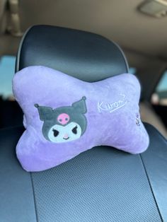 a purple pillow with a black bear on it's side in the back seat of a car