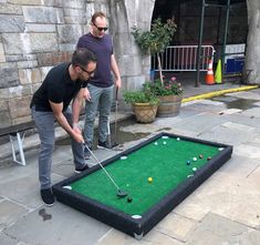 two men playing mini golf on the sidewalk