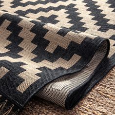 a black and white rug with fringes on top of the carpet, next to an area rug