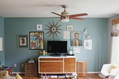 a living room with blue walls and pictures on the wall, including a flat screen tv