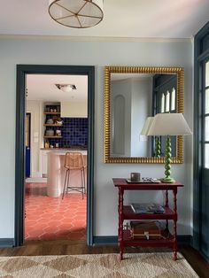 a living room with a red table and mirror