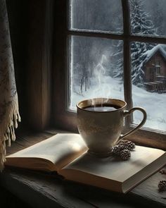 a cup of coffee sitting on top of an open book next to a window sill