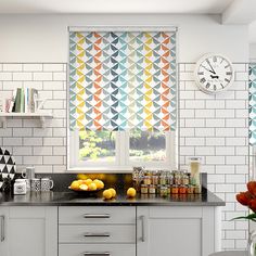 the kitchen is decorated in white and has oranges on the counter, as well as fruit