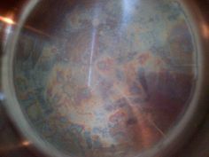 the inside of a metal bowl with some paint on it's surface and light coming from above