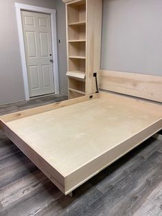 an unfinished bed frame in the middle of a room with open shelving units on either side