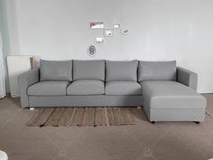 a living room with a gray couch and rugs on the floor in front of a white wall