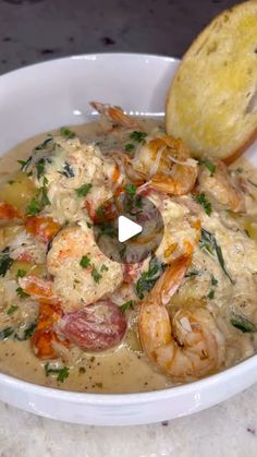 a bowl filled with shrimp and grits next to a piece of bread