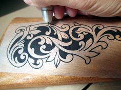 a person is using a pen to draw designs on a piece of wood