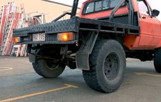 an orange pick up truck parked in a parking lot