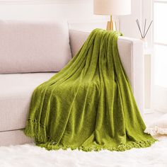 a living room with a white couch and green blanket