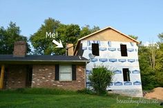 a house being built in the middle of a field with trees and grass around it