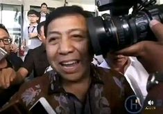 a man holding a camera up to his face in front of other people with cameras around him