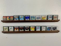 two wooden shelves filled with video games on top of each other in front of a white wall