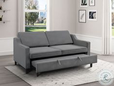 a gray couch sitting on top of a rug in a living room next to a window