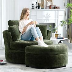 a woman sitting in a green chair with her feet on the coffee table and holding a cup