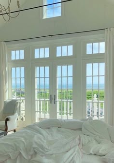 a bedroom with white walls and windows overlooking the ocean