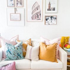 a living room filled with lots of pillows and pictures on the wall above it's couch