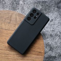 a black cell phone sitting on top of a wooden table next to a gray wall