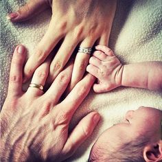 an older person holding the hands of a baby's hand while it lays down