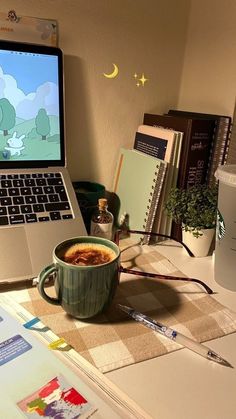 an open laptop computer sitting on top of a desk next to a cup of coffee