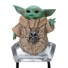 the child yoda toy is sitting on top of a silver tray and holding his hands up