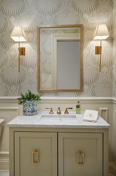 a bathroom with a sink, mirror and two lights on the wall above it's counter