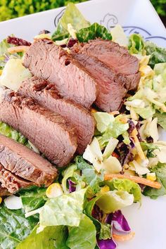 a white plate topped with meat, salad and lettuce next to a fork