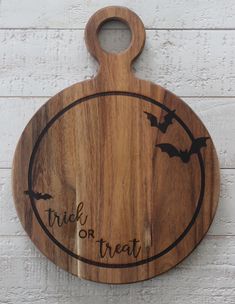 a wooden cutting board that says trick or treat with bats on the front and bottom