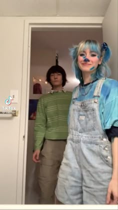 a woman with blue hair wearing overalls and clown nose paint standing in front of a door