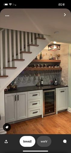 a kitchen with white cabinets and black counter tops next to a stair case in an open floor plan