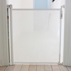 an open door leading to a bathroom with white walls and wood flooring in front of it