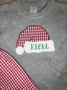 Get ready for holiday fun with this precious Santa hat shirt! This design looks great with a monogram on the brim of the hat! When ordering an embroidered item, please specify your desired design, monogram initials or name, monogram font & thread color. All of the monogram options can be found here. Also, please note any special requests in the box provided. We will try our best to comply. Applique Shirts, Font Names, Christmas Tree Design, Monogram Fonts, Tree Design, Tree Designs, Applique Designs, Monogram Initials, Santa Hat