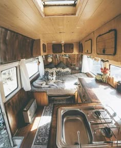 the interior of an rv with wood paneling and stainless steel sink, windows, and cabinets