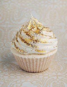 a cupcake with white frosting and gold sprinkles