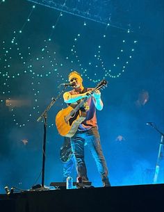 a man standing on top of a stage holding a guitar