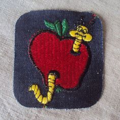 an apple with a worm on it is sitting on top of a cloth material surface